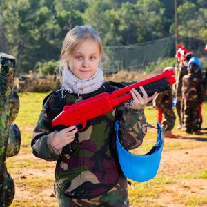 petite fille portant un uniforme et tenant un pistolet prêt à jouer avec des amis sur le paintball