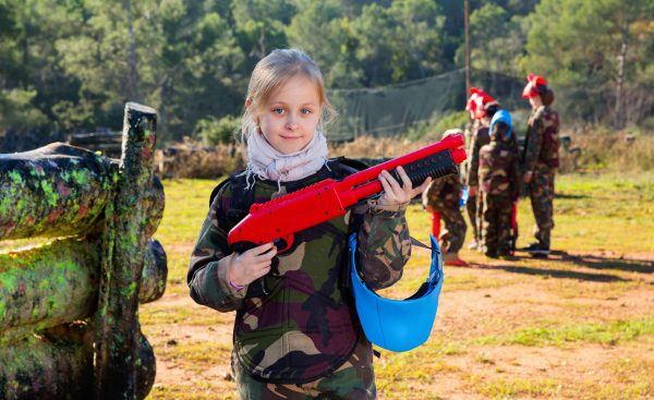 petite fille portant un uniforme et tenant un pistolet prêt à jouer avec des amis sur le paintball